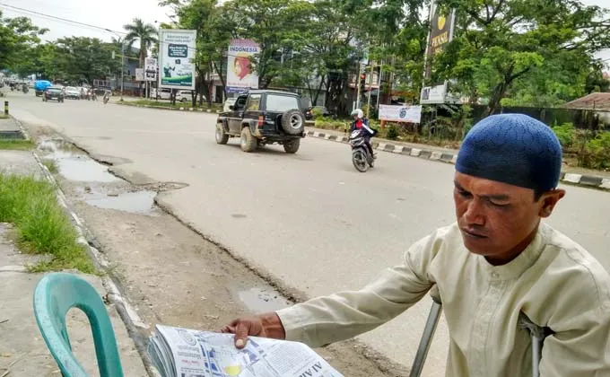 Dibantu Tongkat, Pria Ini Menjual Koran di Lampu Merah