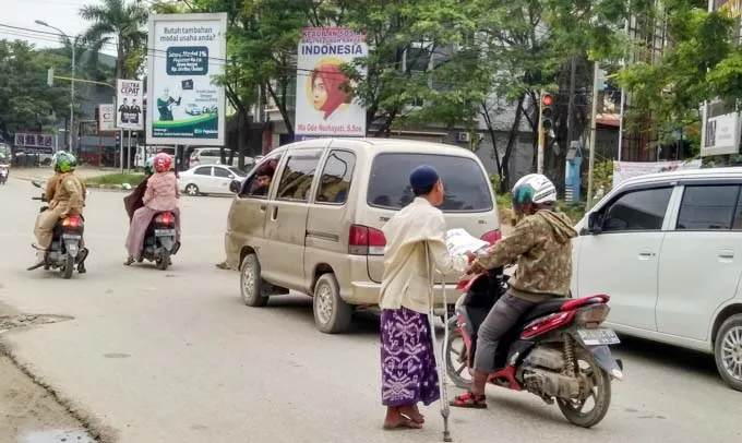 Dibantu Tongkat, Pria Ini Menjual Koran di Lampu Merah