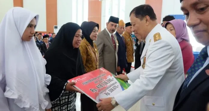 BPJS KETENAGAKERJAAN - Pelaksana tugas (plt) Gubernur Sultra Saleh Lasata saat menyerahkan secara simbolis kepada penerima ahli waris peserta BPJS Ketenagakerjaan sebesar Rp. 418 juta yang didampingi Kepala Cabang BPJS Ketenagakerjaan La Uno (kanan), Kamis (17/8/2017). (ILHAM SURAHMIN/ZONASULTRA.COM)